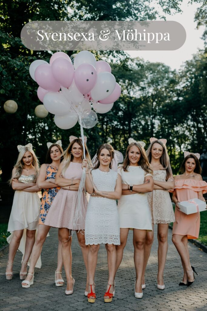 Grupp kvinnor firar möhippa utomhus med ballonger, utklädnad och presenter, glada deltagare i fokus.